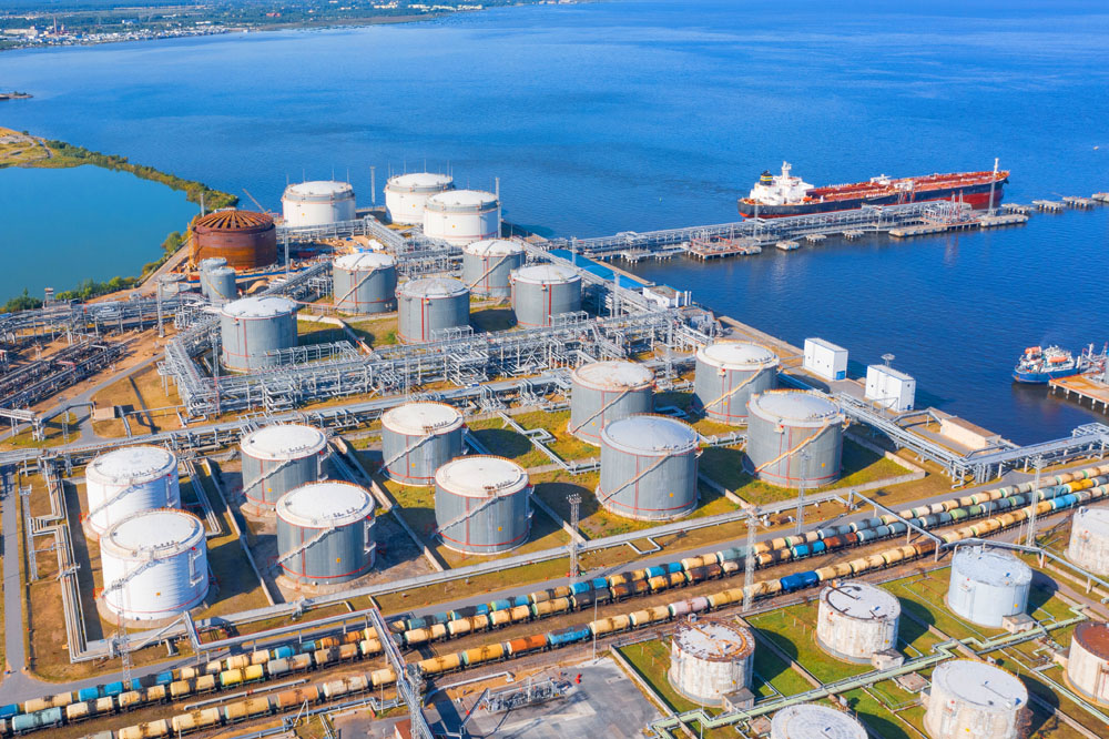 Aerial view of large fuel storage tanks at oil refinery industrial zone in the cargo seaport, and ship tanker at unloading.